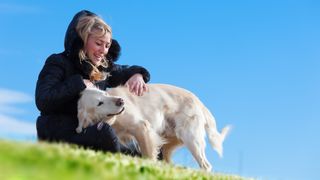 Woman sat with her dog outside on cold and sunny day