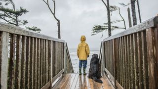 Child and dog standing outside in the wind/rain together