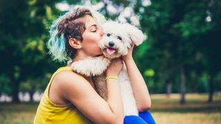 Young woman kissing puppy outdoors